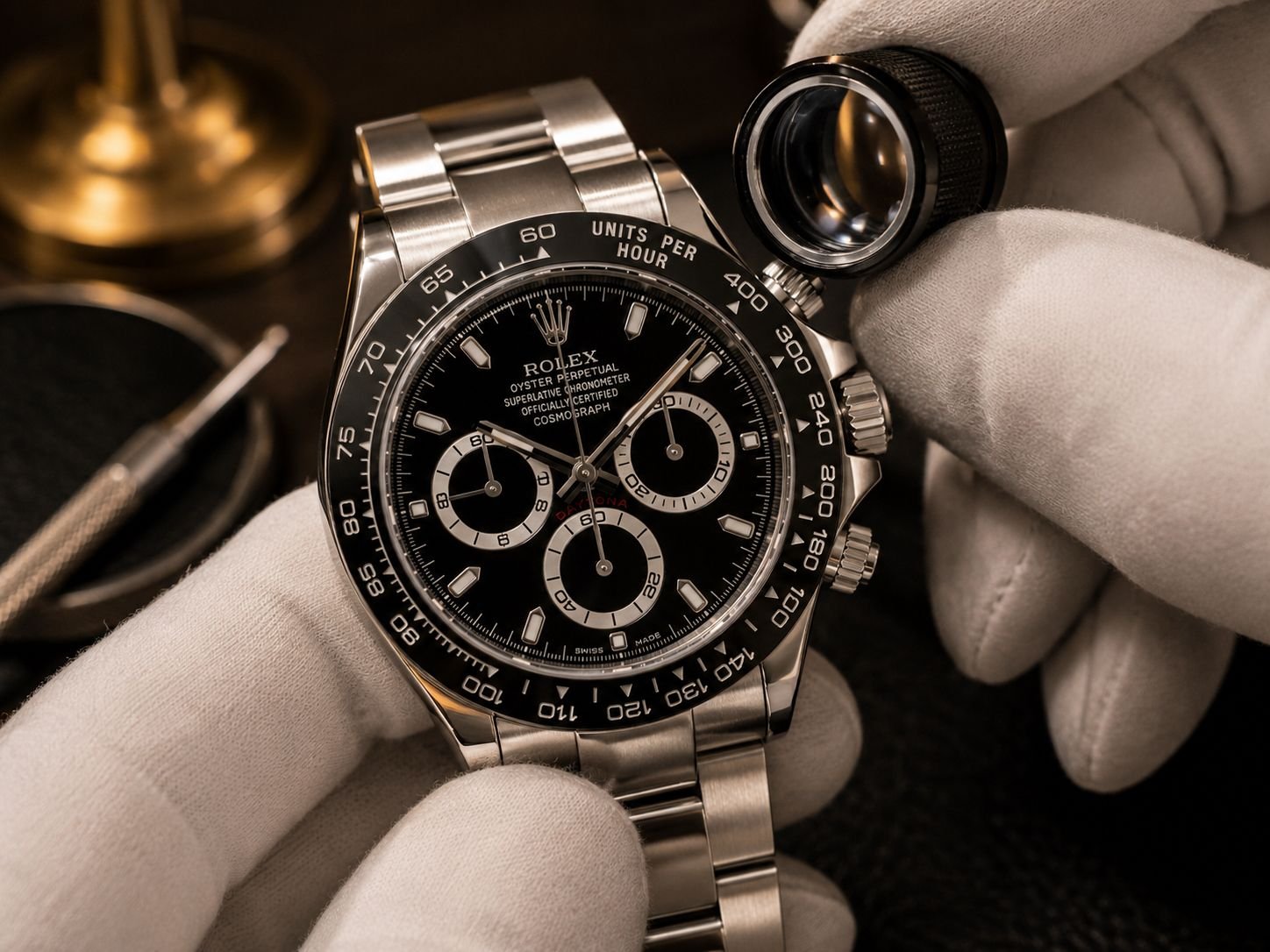 Luxury watch specialist inspecting Rolex Daytona case, bezel, and crystal condition with jeweler loupe under atelier lighting